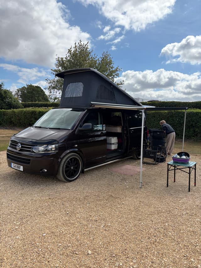 Black camper van with its pop-top roof raised